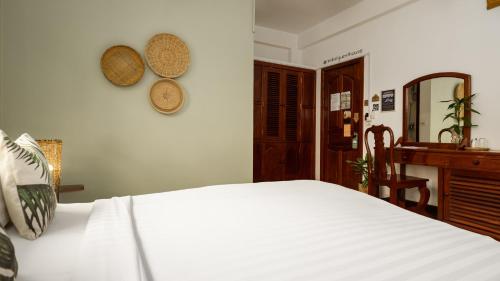 a bedroom with a white bed and a desk at Babel Siem Reap Guesthouse in Siem Reap