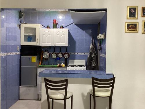 a small kitchen with a counter and two chairs at Entire accommodation Departamento Mi Mexico in Mexico City