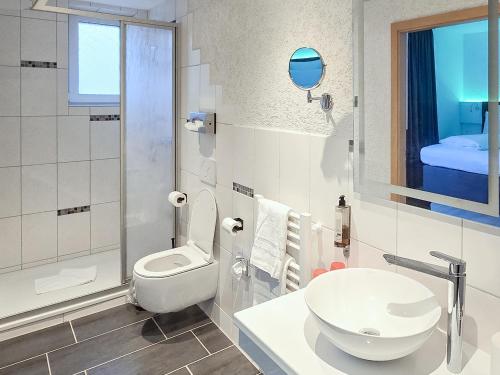 ein weißes Badezimmer mit Toilette und Waschbecken in der Unterkunft DORMERO Moselhotel Koblenz-Alken in Alken