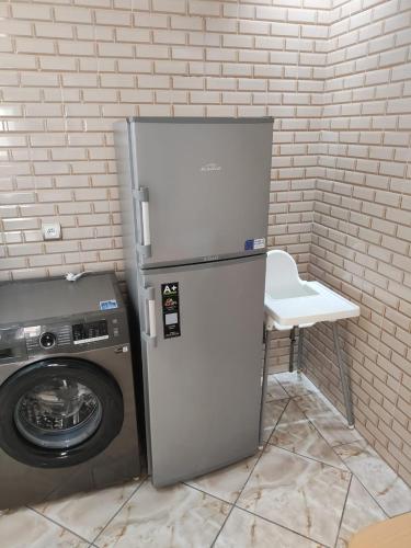 a refrigerator next to a washing machine and a chair at Flat Al farabi in Agadir