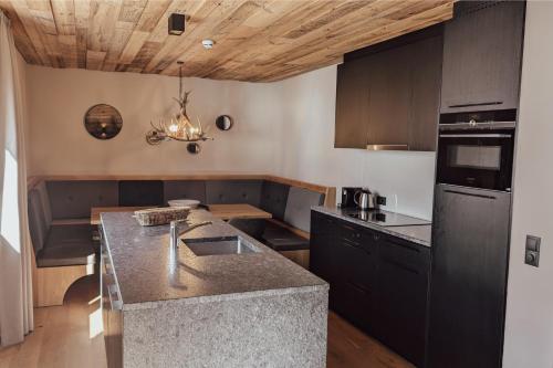 a kitchen with black cabinets and a counter top at AlpenParks Hotel & Apartment Arlberg Warth mit Pool in Warth am Arlberg