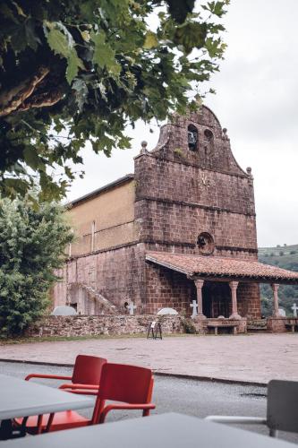 un vieux bâtiment en briques avec deux chaises rouges devant dans l'établissement Hôtel Barberaenea, à Bidarray