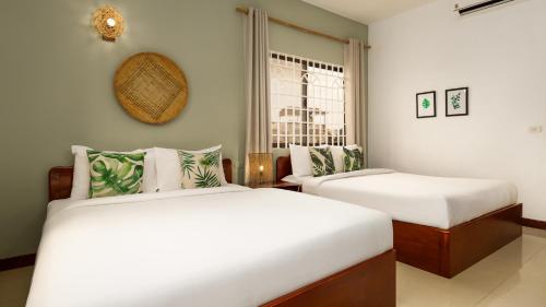 a bedroom with two beds and a window at Babel Siem Reap Guesthouse in Siem Reap