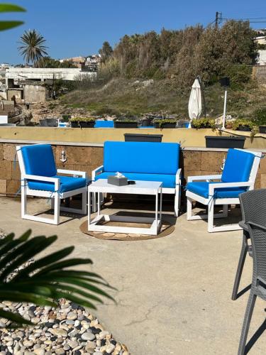 three blue chairs and a table on a patio at Golden Stone Beach in Halat Byblos