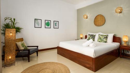 a bedroom with a bed and a chair in a room at Babel Siem Reap Guesthouse in Siem Reap