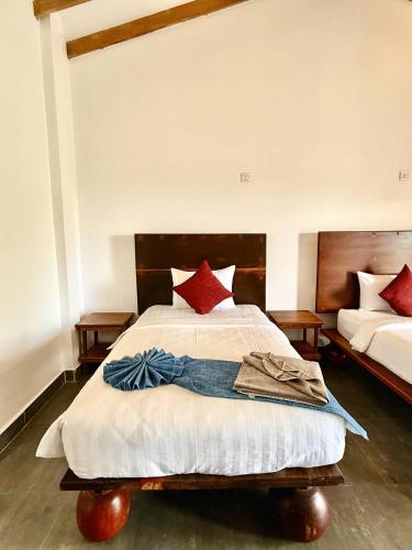 a bedroom with a large bed with red pillows at PIDA COFFEE FARM LODGE in Phumĭ Pu Pal