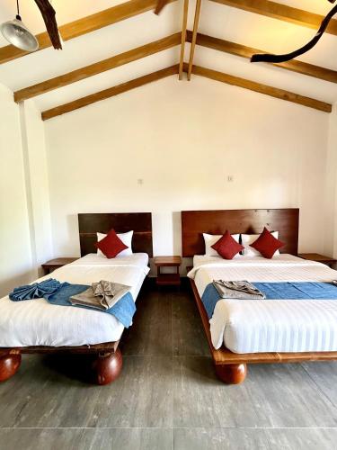 two beds in a room with wooden floors and ceilings at PIDA COFFEE FARM LODGE in Phumĭ Pu Pal