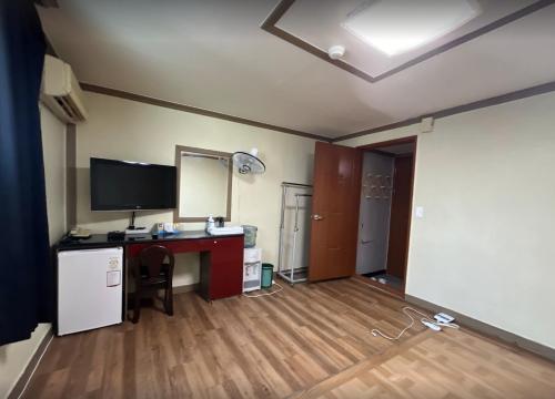 a room with a desk with a computer and a television at Sangmu Green Hotel in Gwangju