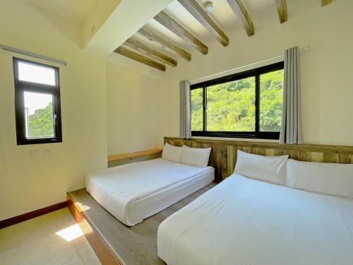 two beds in a room with two windows at OceanSeeker in Green Island
