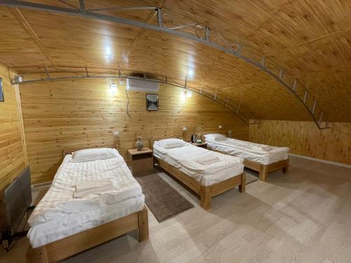 two beds in a room with a wooden wall at Guest house Amirhan in Bokonbayevo