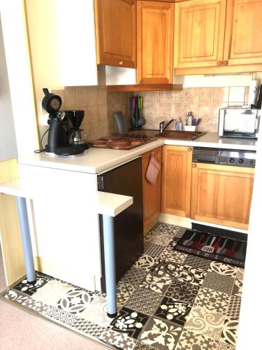 une cuisine avec des armoires en bois et un sol carrelé dans l'établissement Super Deauville, à Villers-sur-Mer