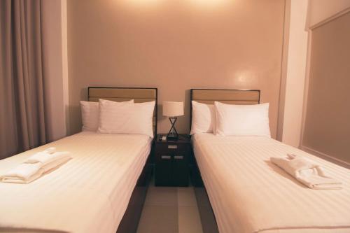 two beds in a room with white sheets at Aura Condotel in Roxas City