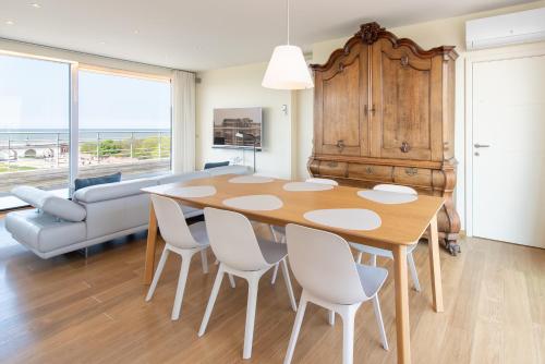 a dining room with a table and chairs and a couch at Penthouse Ostend with Seaview in Ostend