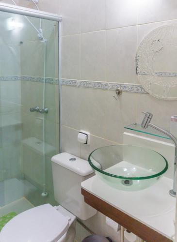 a bathroom with a glass sink and a toilet at Pousada Irashai in Juquei