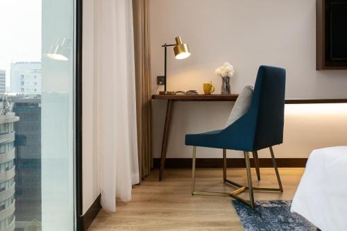 a room with a desk and a blue chair at Mövenpick Living West Hanoi in Hanoi