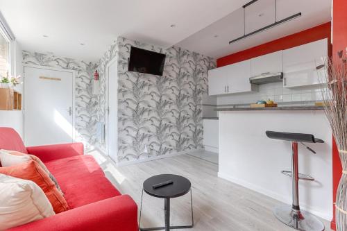 un salon avec un canapé rouge et une cuisine dans l'établissement Charming Gambetta Saint Fargeau I apartment, à Paris