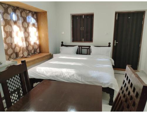 斋沙默尔Hotel Namaste jaiselmer inn, Jaiselmer的一间卧室，配有两张床、一张桌子和窗户