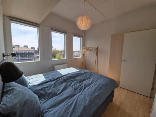 a bedroom with a large bed and two windows at Urban Stay Herning in Herning