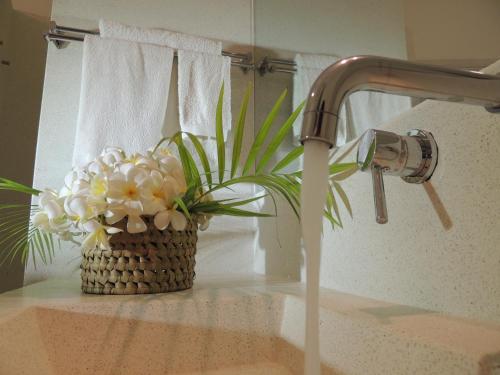 a bathroom sink with a faucet and a basket of flowers at The Kasa Malindi in Malindi