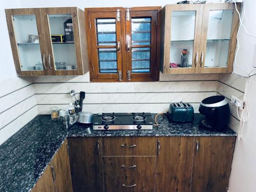 a kitchen with wooden cabinets and a counter top at Dhawanfarms in Bela