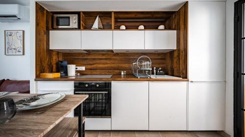 - une cuisine avec des placards blancs et un mur en bois dans l'établissement Le loft sur rivière, à Dijon