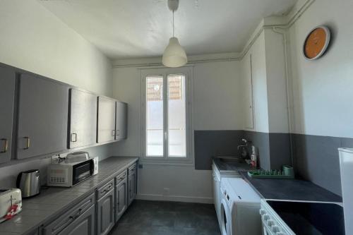 une cuisine avec un évier et un micro-ondes dans l'établissement Le nid Havrais, au Havre