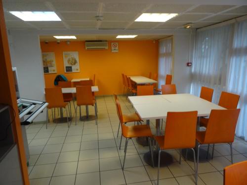 a dining room with orange chairs and tables at Premiere Classe Lyon Sud - Chasse Sur Rhône in Chasse-sur-Rhône