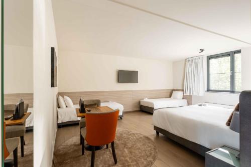 a hotel room with two beds and a desk at Hof van Stayen in Sint-Truiden