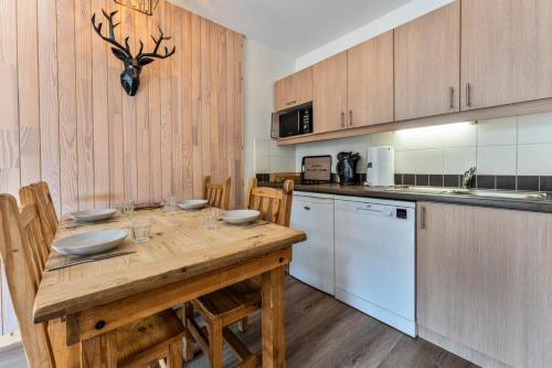 une cuisine avec une table en bois, des chaises et des appareils électroménagers dans l'établissement Résidence Le Balcon Des Airelles - Appartement chaleureux au coeur des Orres 1800 MAE-3661, aux Orres