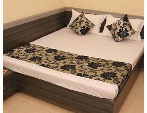 a bed with black and white pillows on it at Hotel heena plaza, mount abu in Mount Ābu