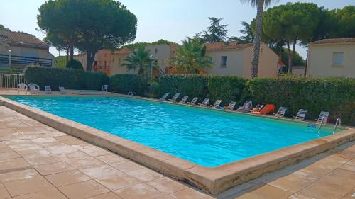 une grande piscine bleue avec des chaises et des arbres dans l'établissement L'Agathoise - Proche de la Plage, au Cap d'Agde