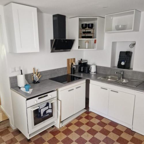 une petite cuisine avec des armoires blanches et un évier dans l'établissement Havre de paix, à Bains-les-Bains