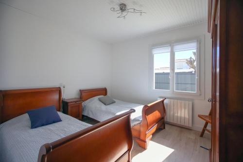 une chambre avec deux lits et une fenêtre dans l'établissement Le Murmure des Vagues - Proche plage, à La Tranche-sur-Mer