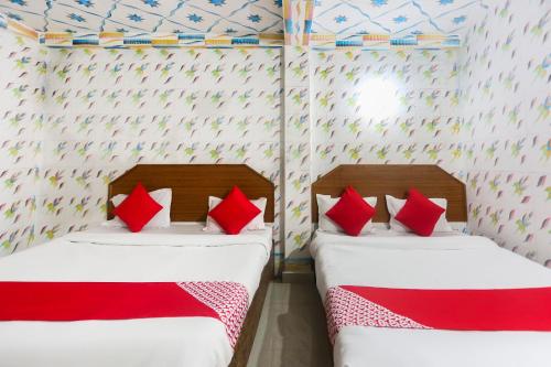 two beds in a room with red pillows at Hotel O Shriram Hotel in Puri