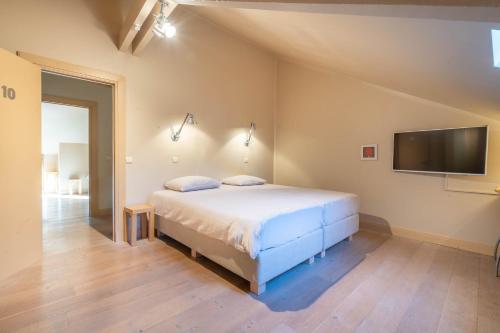 a bedroom with a bed and a flat screen tv at Domein Marsnil in Heers