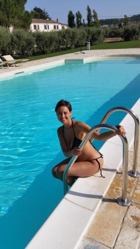 a woman in a bathing suit sitting next to a swimming pool at Agriturismo B&B La Sterpina in SantʼArcangelo