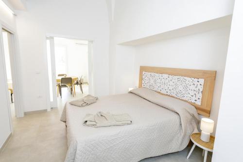 a white bedroom with a bed with a towel on it at Lo Scirocco in Nardò