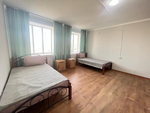 a bedroom with two beds in a room with wooden floors at Мотель 32 in Aktobe