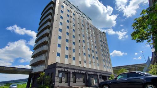 a tall building with a car parked in front of it at Hotel Route-Inn Kameyama Inter in Kameyama