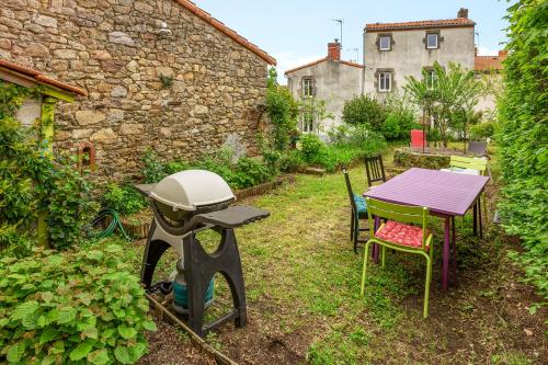 a grill in a yard with a table and chairs at La Petite Fouques - Confortable et paisible in Cugand
