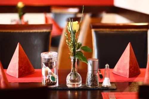 a table with a vase with a flower in it at Landhaus Hammoor Stieper Gastronomie GmbH in Hammoor