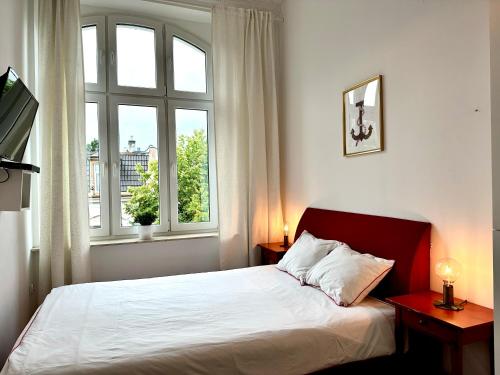 a bedroom with a bed and two windows and a television at Pokoje na Monte Cassino 26 in Sopot