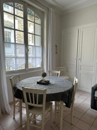 une salle à manger avec une table, des chaises et des fenêtres dans l'établissement Appartement traversant - 20m plage - Cours privée, à Les Sables-dʼOlonne
