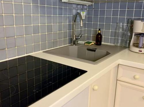 - une cuisine avec un évier et du carrelage bleu dans l'établissement Appartement traversant - 20m plage - Cours privée, à Les Sables-dʼOlonne