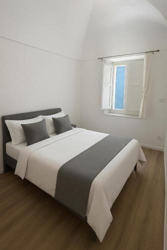 a white bedroom with a large bed with a window at Blusanvito in San Vito lo Capo