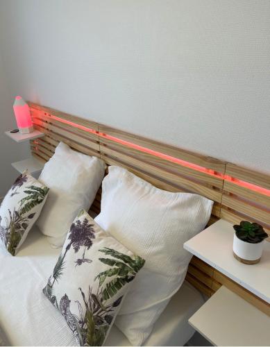 - un lit avec quatre oreillers et une tête de lit en bois dans l'établissement Le rivage du petit serein Vannes, à Vannes