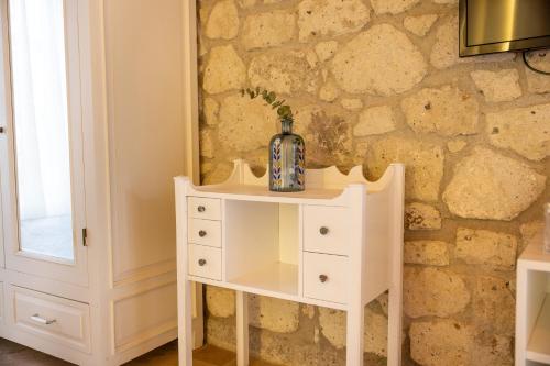 Un tocador blanco con un espejo en una pared de piedra. en La Grenadine Hotel, en Alacati