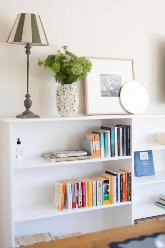 a white book shelf with books and a lamp at Charming Guesthouse in Kyneton in Kyneton