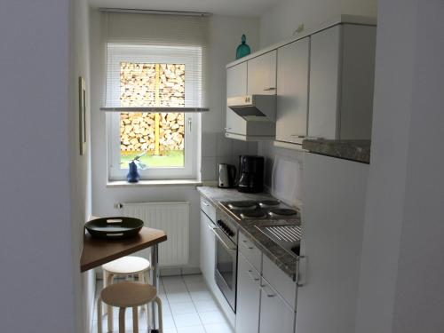 cocina con armarios blancos, mesa y ventana en Ferienwohnung Nimritz, en Oppurg