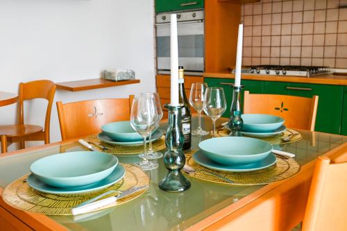 a table with plates and wine glasses on it at Casa Azul - Social Apartment - parcheggio, clima, 200mt dal mare in Scoglitti